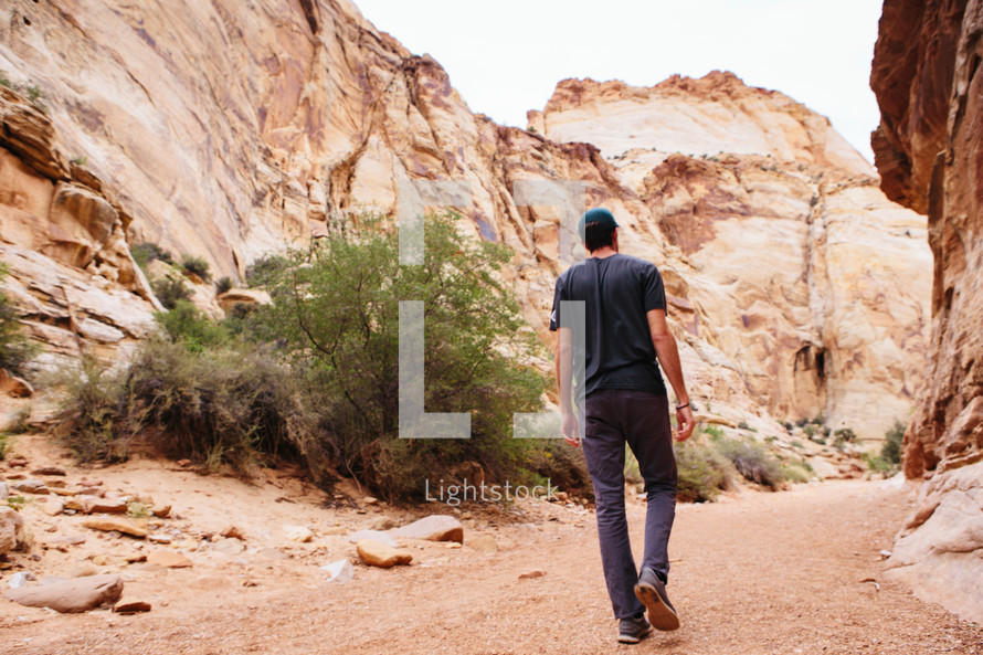 A man walking along a path in a canyon.