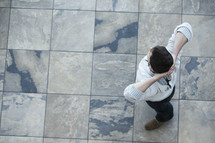 Aerial view of a man standing on tiles with his hands behind his head.