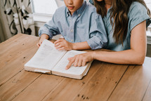 a mother and son reading a Bible together 