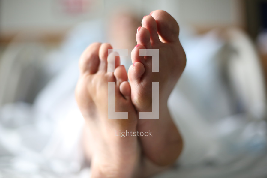 Feet of a woman lying in bed.