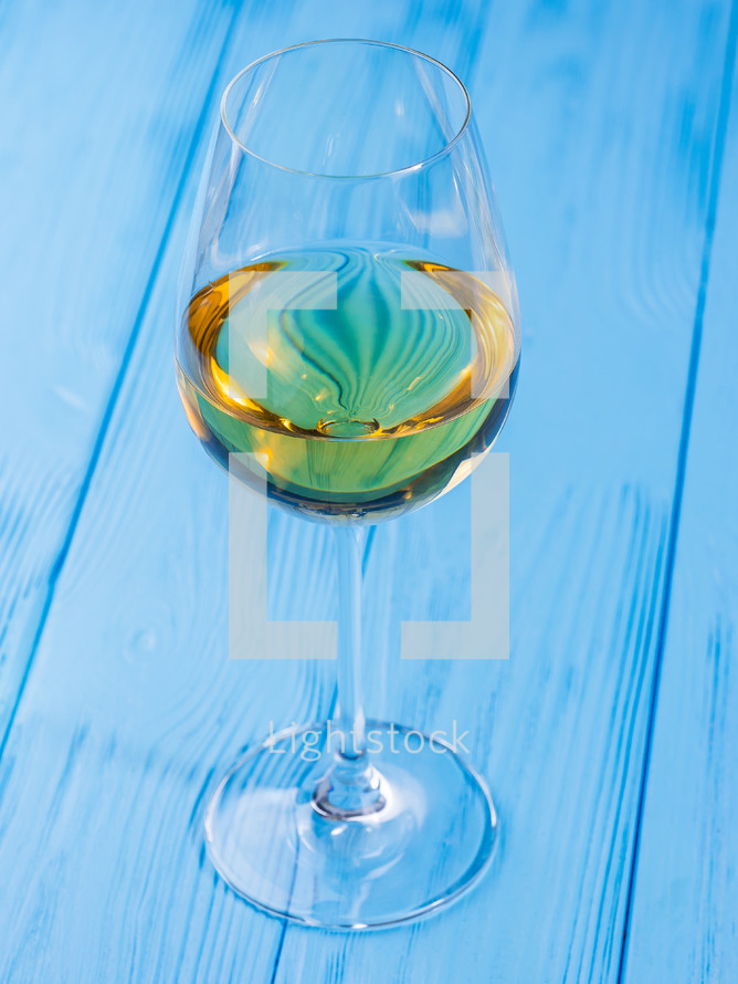 Glass of white fine wine on vintage shabby blue wooden table in restaurant