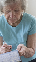 elderly woman writing a check to pay her bills