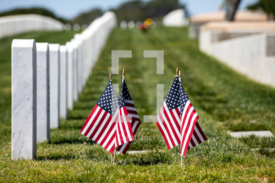 grave markers in a cemetery and American flags 