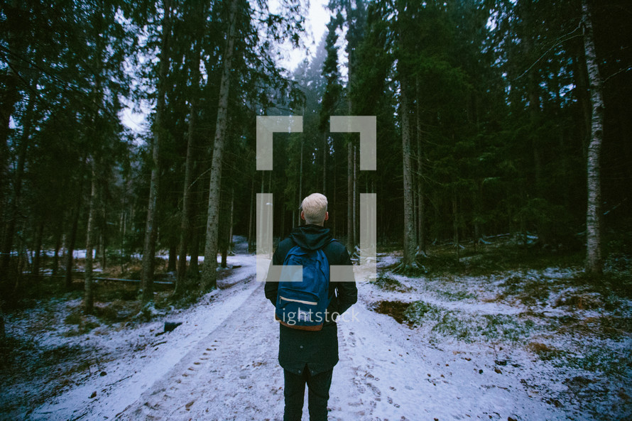 man backing packing through a forest in winter 