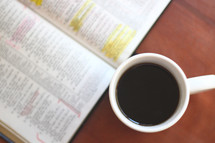 coffee mug and highlighted pages in a Bible 