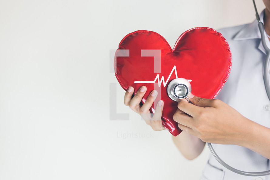 healthcare worker holding a heart and stethoscope 