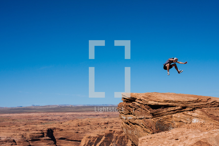 Person jumping on rocky cliff outside.