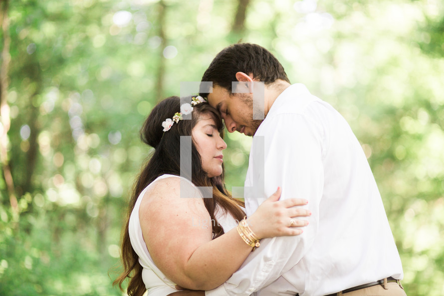 bride and groom embracing in the woods 