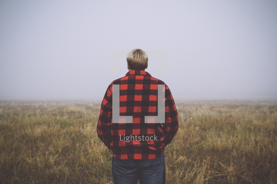 man in a plaid shirt with his back turned to the camera 