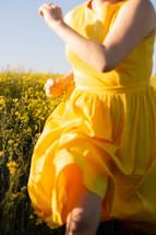 Girl running in a yellow field of flowers