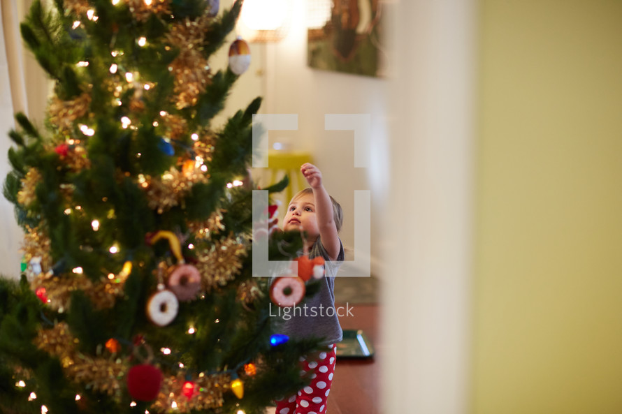 a toddler decorating a Christmas tree