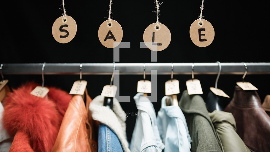 Sale tags hanging with clothes on the background 