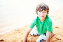 boy child sitting in sand on a beach