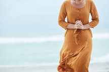 a woman standing on a beach and praying 