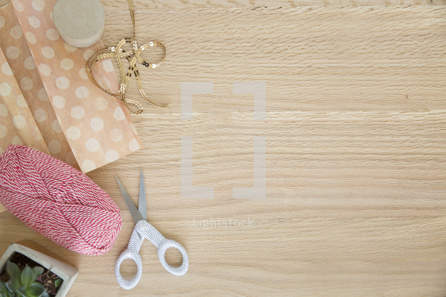 tissue paper, house plant, scissors, yarn, gold, ribbon on wood 
