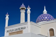 White Islamic Mosque with blue dome against blue sky 
