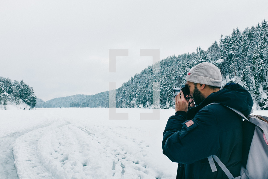 a man standing in snow taking pictures with a camera 
