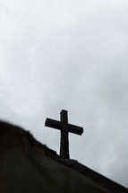 The silhouette of a cross against a gray sky.