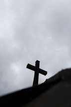 The silhouette of a cross against a gray sky.