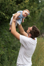 father holding up his infant daughter 