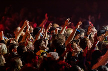youth in an audience with hands raised 