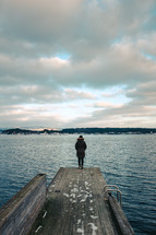 a woman standing at the end of a dock in winter 