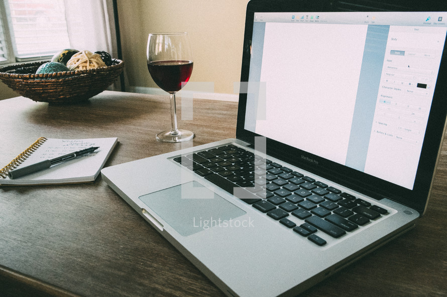 wine glass, laptop, pen, and notepad
