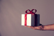 A hand holding out a gift box