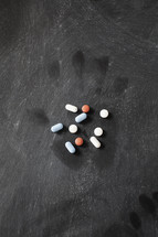 pills on a dark table with faint handprint mark