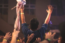 a man standing up in church with raised hands 