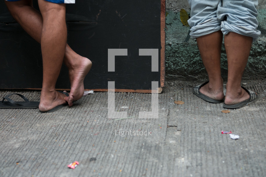 feet in sandals on a sidewalk 