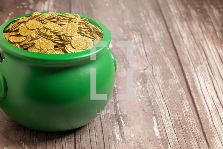 Pot Full of Golden Coins Isolated on a Wood Background