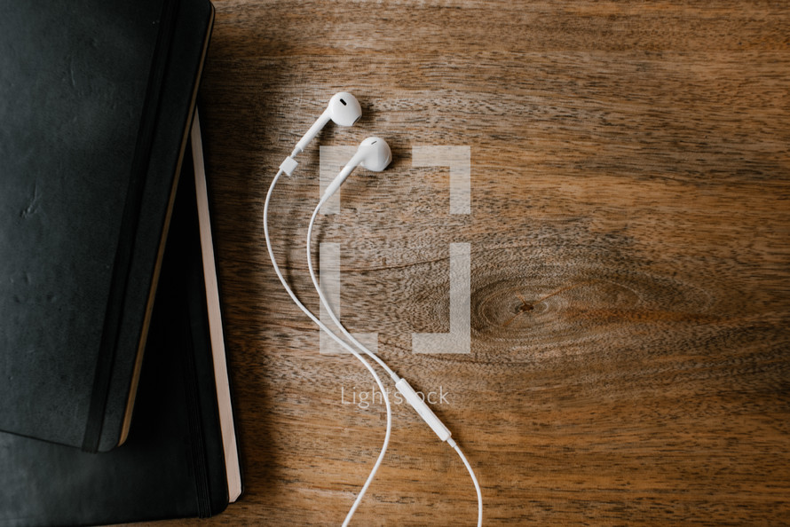earbuds, Bible, and journal on a wood table 