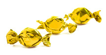 three gold wrapped candies on a white background 