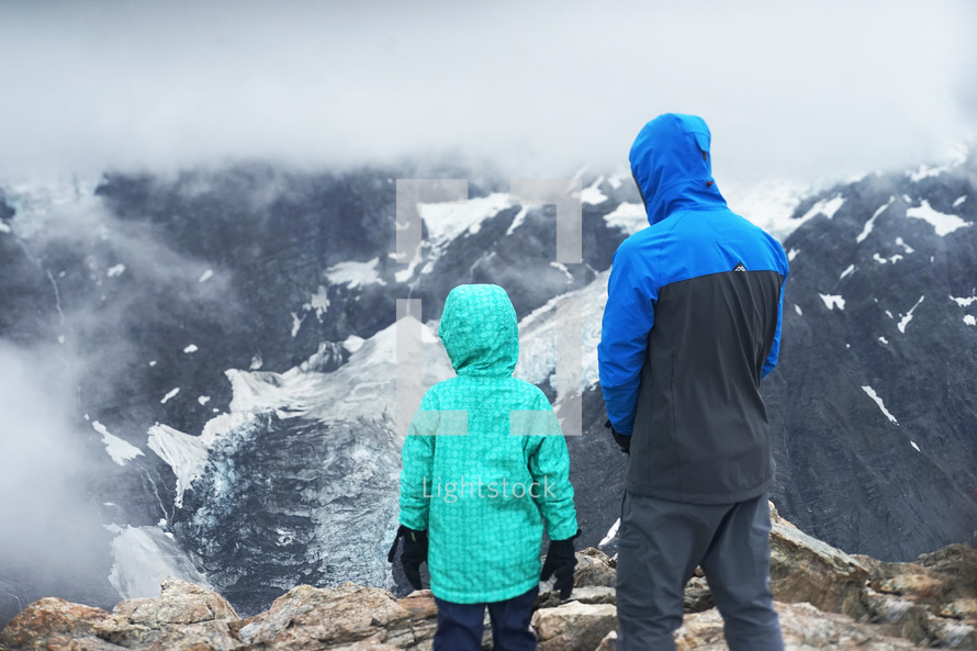 father and son standing on top of a mountaintop 