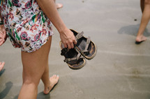 woman walking barefoot carrying her sandals 