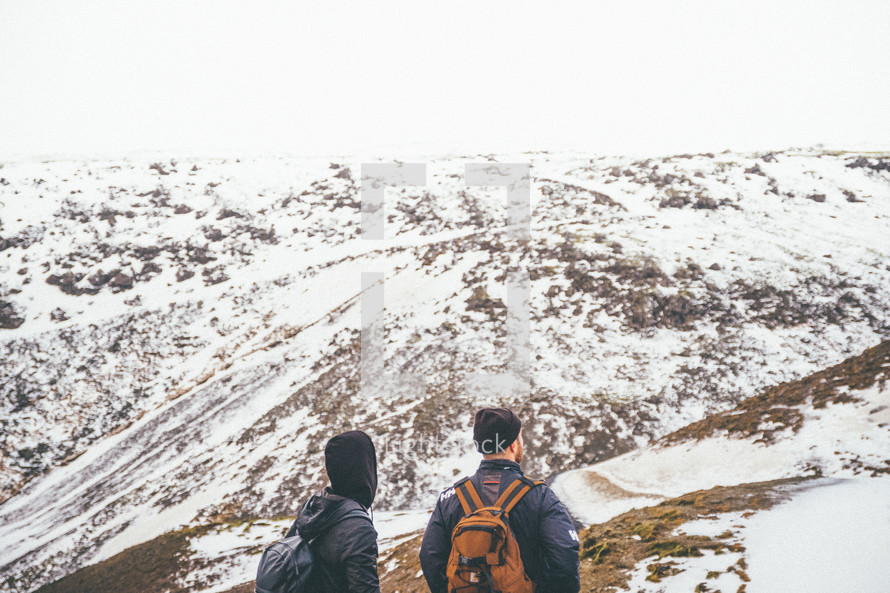 two men hiking up a snow covered mountain 