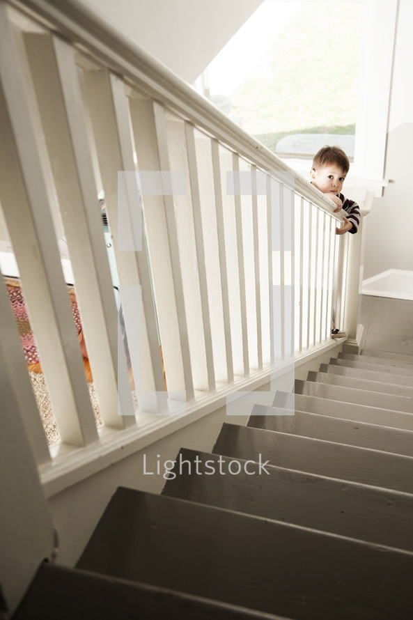 toddler peeking at the bottom of the stairs 