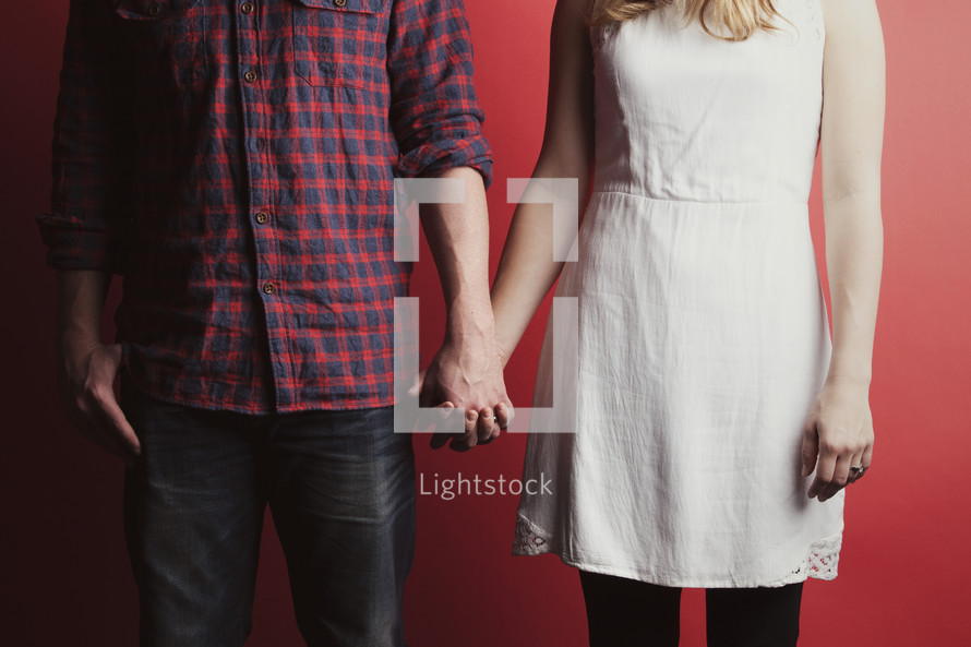 A couple holding hands with a red background