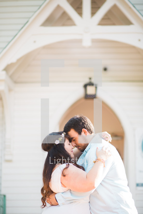 bride and groom embracing in front of a church 