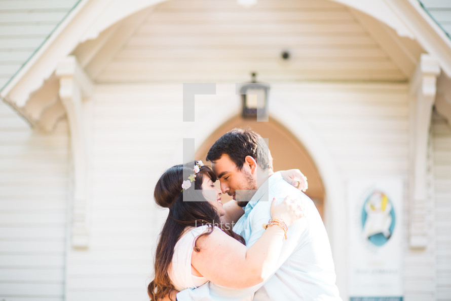 bride and groom embracing in front of a church 