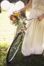 a bride pushing a bicycle with a basket of flowers