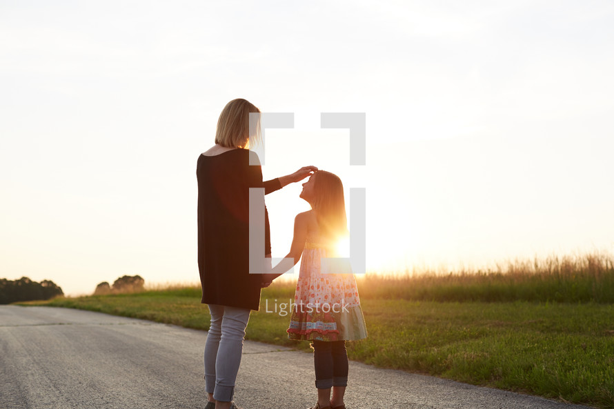 a mother and daughter standing together outdoors 