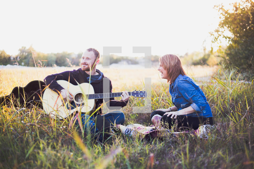 man playing a guitar for a woman outdoors 