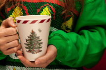 woman in a Christmas shirt holding a mug 