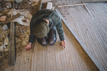 A woman prays on the floor of an abandoned house.