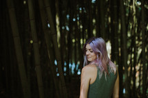 a woman with pink hair standing in front of a bamboo forest 