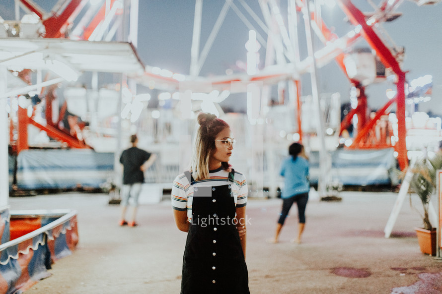 teen girl standing in front of a ferris wheel 