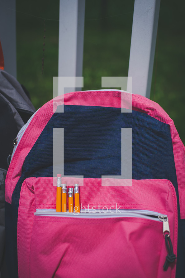 pink and gray book bags with pencils in the pockets