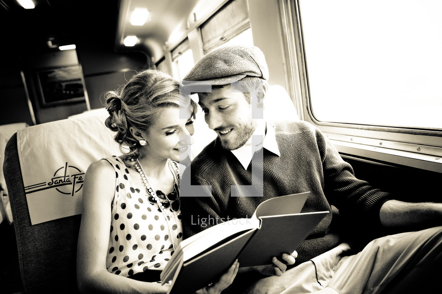 Couple reading a book together while traveling on a train.